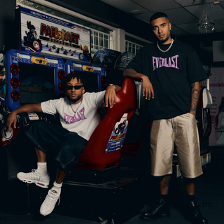 To mænd, Oliver Kesi og Benny Jamz, poserer foran et arkadespil, iført oversized Everlast-T-shirts med fed pink skrift. Den ene sidder i en rød arkadestol 